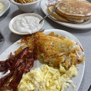 a breakfast of eggs, bacon, hash browns, pancakes, and pancakes