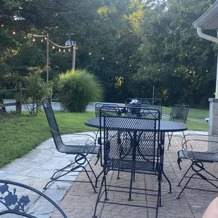 Side patio with three metal tables, rose bushes and hanging lights