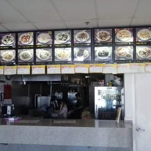 a restaurant counter with menus on the wall