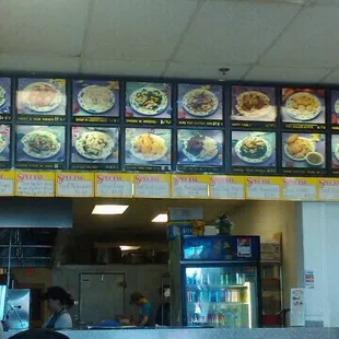 a restaurant counter with menus on the wall