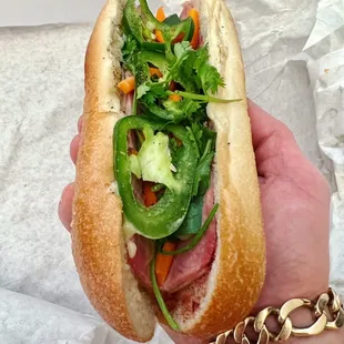 a hand holding a sub sandwich