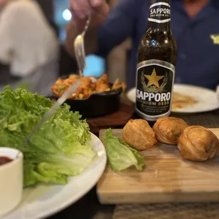 a man sitting at a table with food and a beer