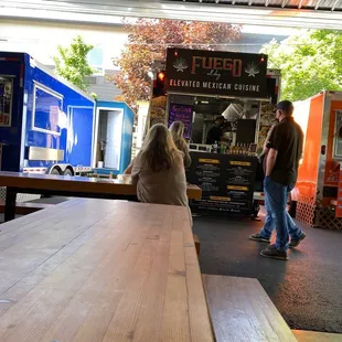 a man and a woman standing in front of a food truck