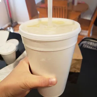 a hand holding a cup with a straw