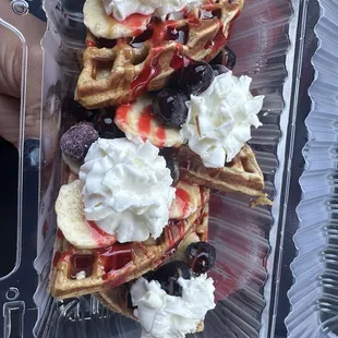Protein waffles with bananas and blueberries, Carmel and strawberry drizzle.