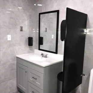 a bathroom with a sink, mirror, and towel dispenser