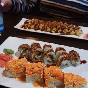 a woman sitting at a table with plates of sushi