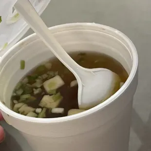 a person holding a spoon in a cup of soup