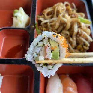 a bento box of sushi with chopsticks