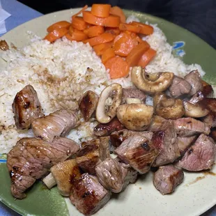 a plate of meat, rice and carrots