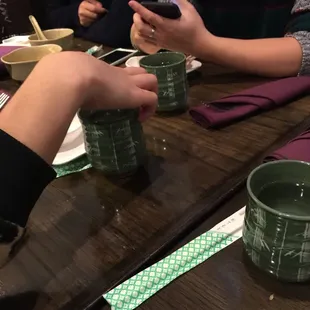 two people sitting at a table with cups of tea