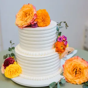 a white wedding cake with orange and pink flowers