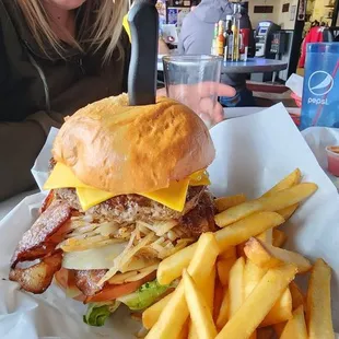a woman sitting at a table with a sandwich and fries