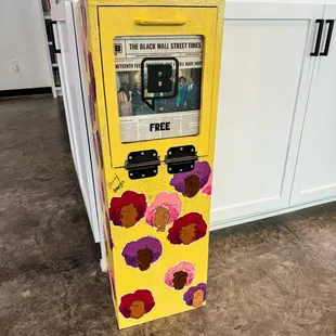 a yellow vending machine with flowers painted on it