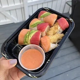 a person holding a tray of sushi