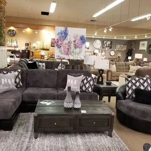 Two-tone dark sofa chaise shown with matching swivel chair. Some, but not all pillows are included.