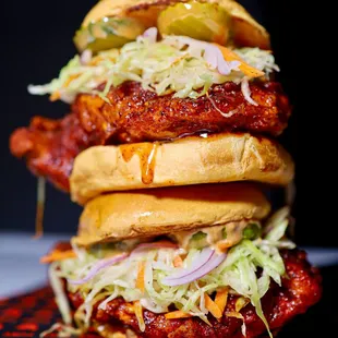 a stack of sandwiches with meat, coleslaw, and pickles