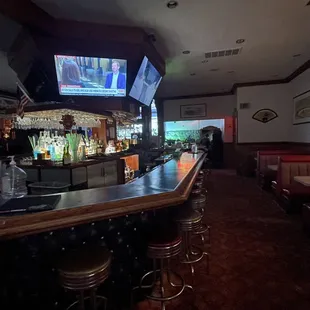 a view of a bar with bar stools and televisions