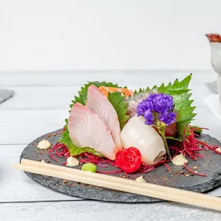 a plate of sushi with chopsticks