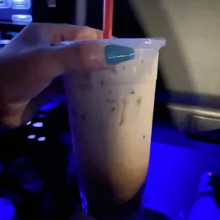 a hand holding a cup of iced coffee