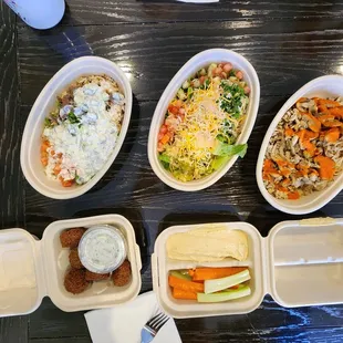 Clockwise from the top left, steak bowl, chicken salad, chicken bowl, hummus with veggies and falafel with cucumber sauce.