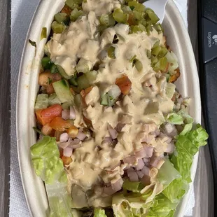 Bowl with lettuce, rice, hummus, potatoes, chicken, pickles and pickles turnips, and spicy tahini on top!