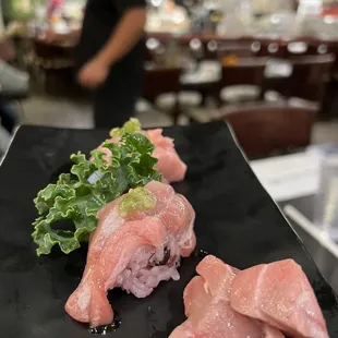 two pieces of sushi on a black plate