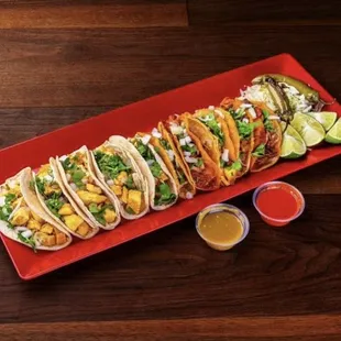 a long platter of tacos with a variety of toppings