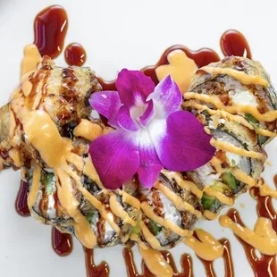 a plate of sushi with sauce and a flower