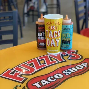 a taco shop table with a cup of hot sauce