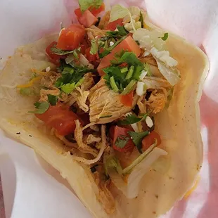 Shredded chicken  soft taco about to be smothered with butt burning hot sauce