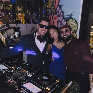 a man and two women at a dj booth