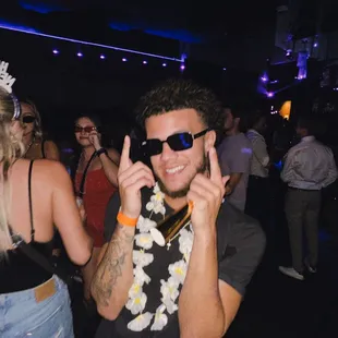 a man in a flowered shirt and sunglasses talking on a cell phone