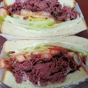 Pastrami in white bread with mayo, lettuce and tomato.