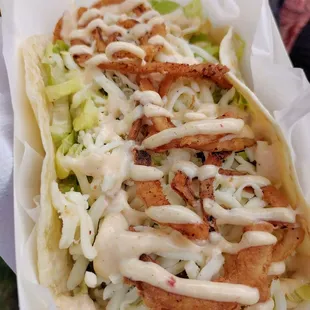 a close up of a taco with lettuce and sauce