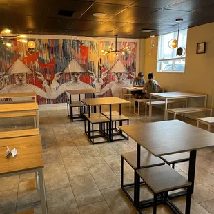 the interior of a restaurant with tables and benches