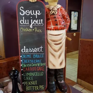 a statue of a chef holding a chalkboard