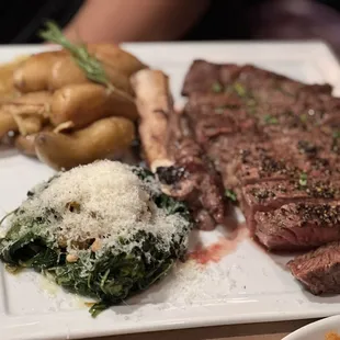 a plate of steak, potatoes, and spinach