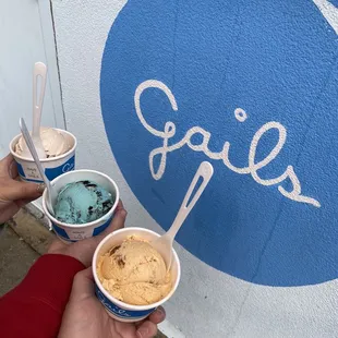 a hand holding two cups of ice cream