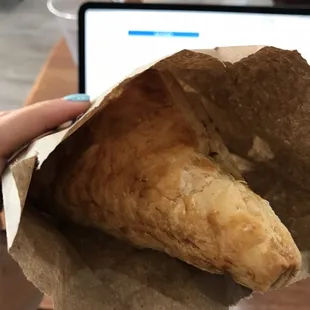 a person holding a pastry in a paper bag