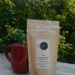 a bag of coffee next to a red mug