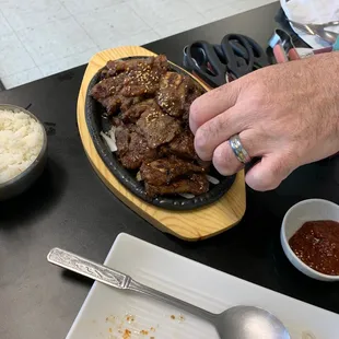 a person putting sauce on a plate of food