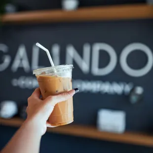 a hand holding a cup of iced coffee