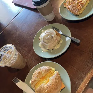 Egg and cheese bagel sandwich, cinnamon roll, sausage and red pepper quiche, banana cream iced latte, americano