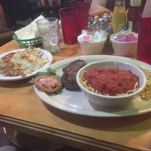Steak with a side of spaghetti and hash browns. A quirky combo.