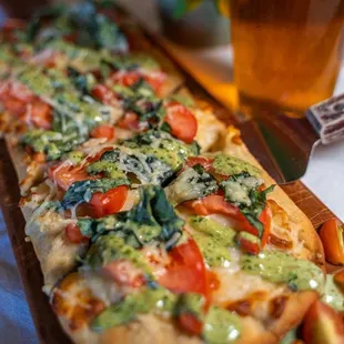 a pizza with tomatoes, spinach, and cheese