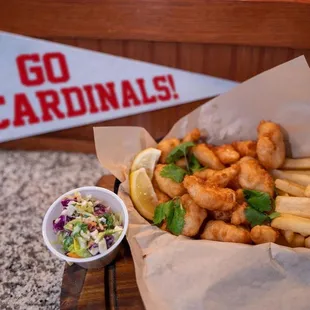 a basket of fish and fries with a side of coleslaw