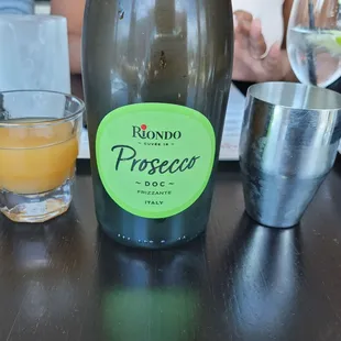 a bottle of prosecco next to a glass of orange juice