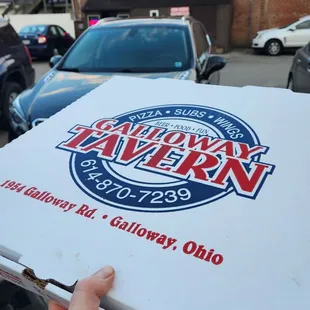 a hand holding a box of pizza