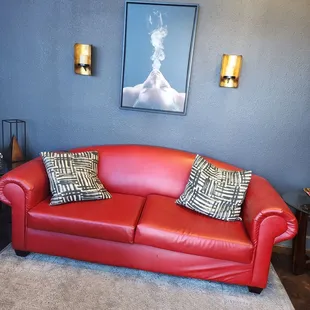 a red leather couch with two pillows